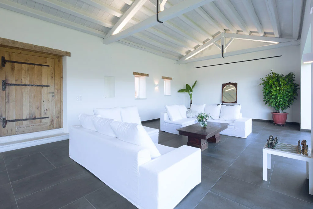 A villa living room showing white sofas and slate flooring with white walls