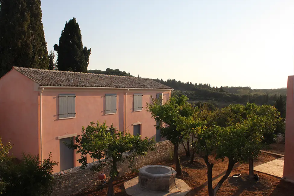 Evening sunshine on a Courti Estate building with olive trees in the garden