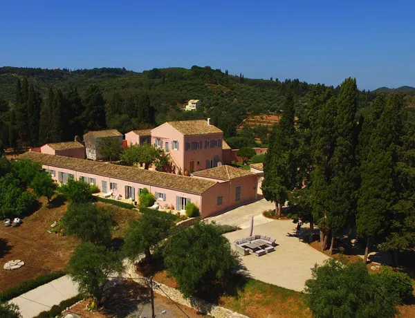 Aerial view of The Courti Estate, a hilltop villa set in a large green open space on the island of Corfu.