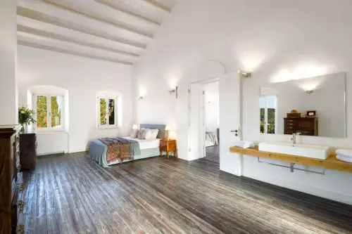 Bedroom with wooden flooring and white sink with mirror