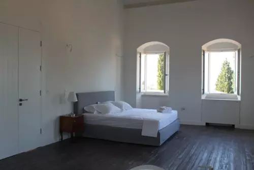 A bedroom at The Courti Estate with white walls and bed sheets