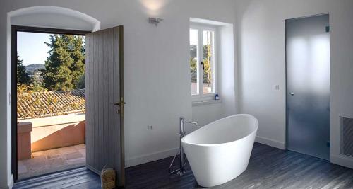 A villa bathroom showing a white free standing bath with chrome taps with a doorway leading outside.