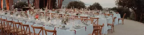 Outdoor wedding reception seating with string lights on during early evening
