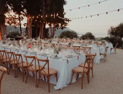 Outdoor wedding reception seating with string lights on during early evening