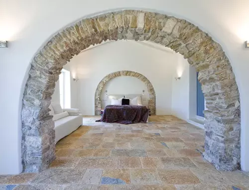 A Courti Estate Bedroom with stone archway, white walls and dtone flooring.